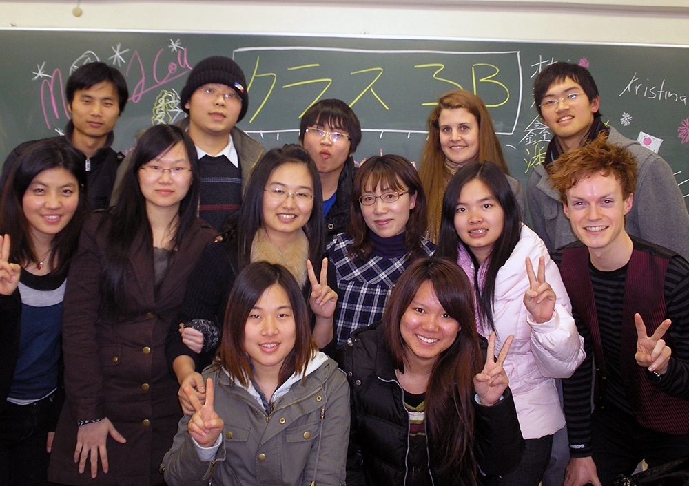 Marcus posing in front of a blackboard with fellow students at Bunkyo University
