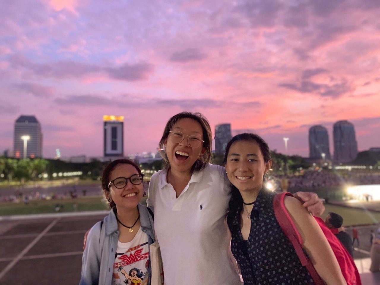Sherry with two Indonesian students with a pink sunset in the background