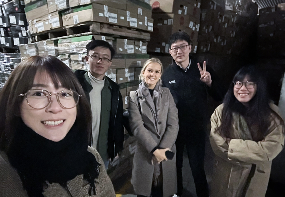 Lori and work colleagues posing for a photo in a warehouse