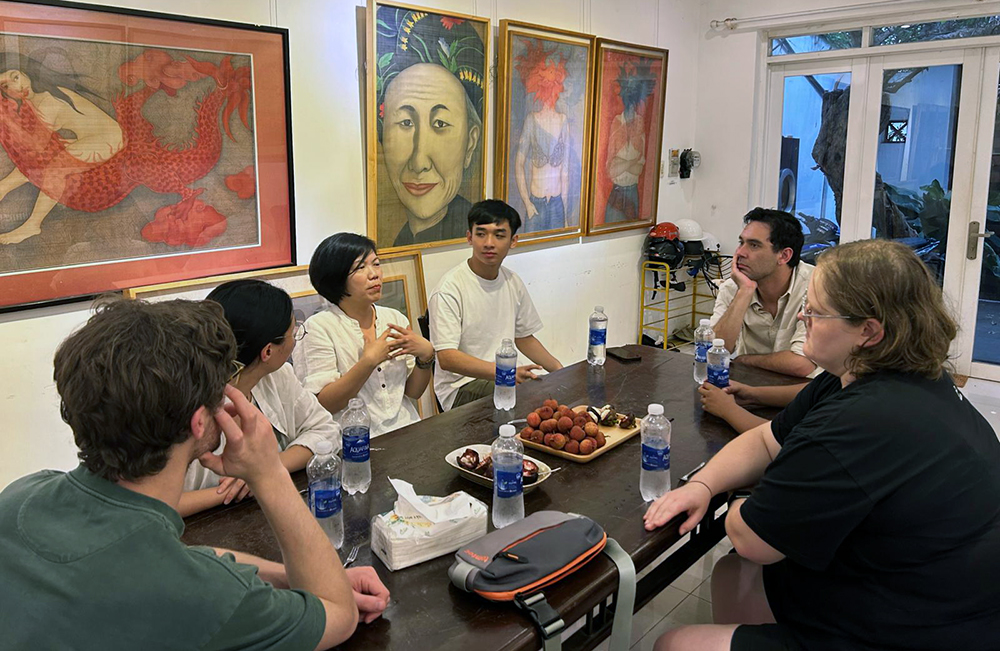The curators sitting at a table listening to artist , Nguyen Thi Chau Giang 