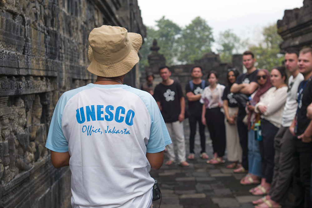 A man wearing a UNESCO t-shirt speaking to the Leadership Network members at Borobudur Temple