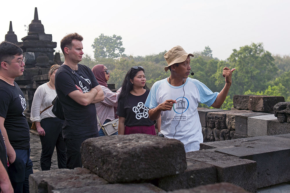 A guide pointing at something out (of shot) to Leadership Network members at Borobudur Temple in Indonesia