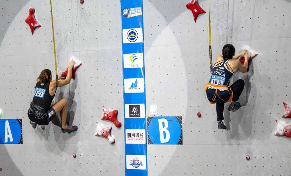 Two female climbers racing up a climbing wall