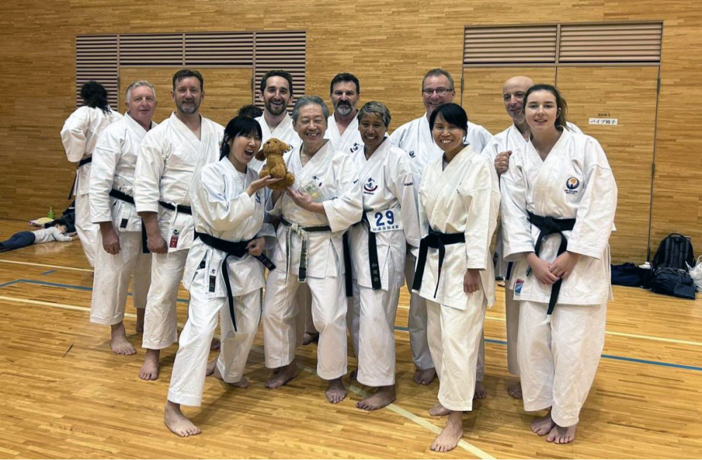 A group shot of the team in a gym in their karate uniforms 